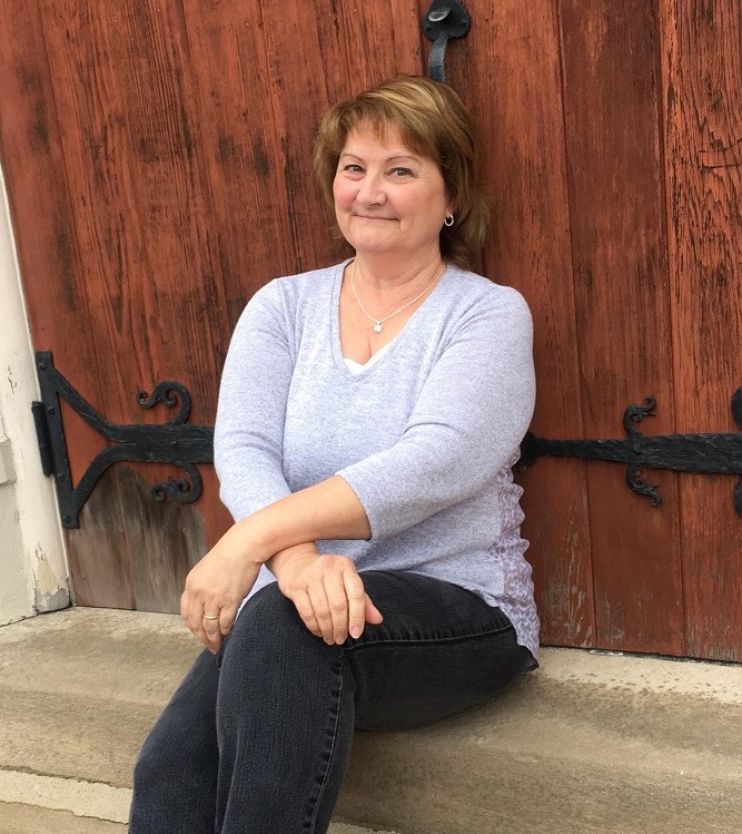 A very sassy adventuress named Monica McCabe sitting against a dark brown door