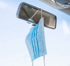 Car rearview mirror with mask hanging from it.