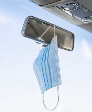 Car rearview mirror with mask hanging from it.